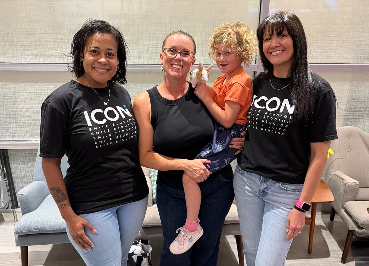 Happy child patient being held by mother standing next to Icon Pediatric Dentistry Technicinas